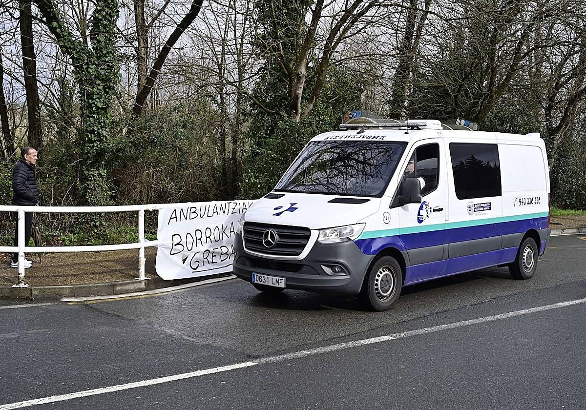 Una ambulancia pasa por delante de un cartel de protesta.