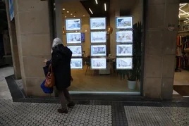 Una mujer mira el escaparate de una inmobiliaria.
