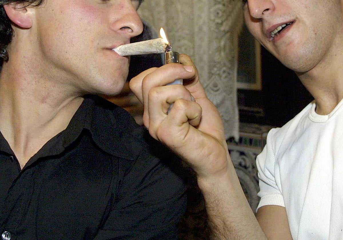 Un joven enciende un porro a otro.