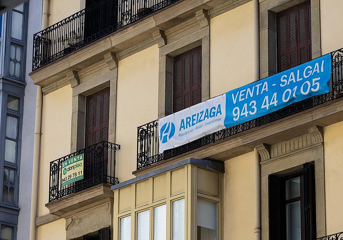 Dos viviendas en venta con carteles de inmobiliarias colgados en sus balcones en el centro de Donostia, ayer.