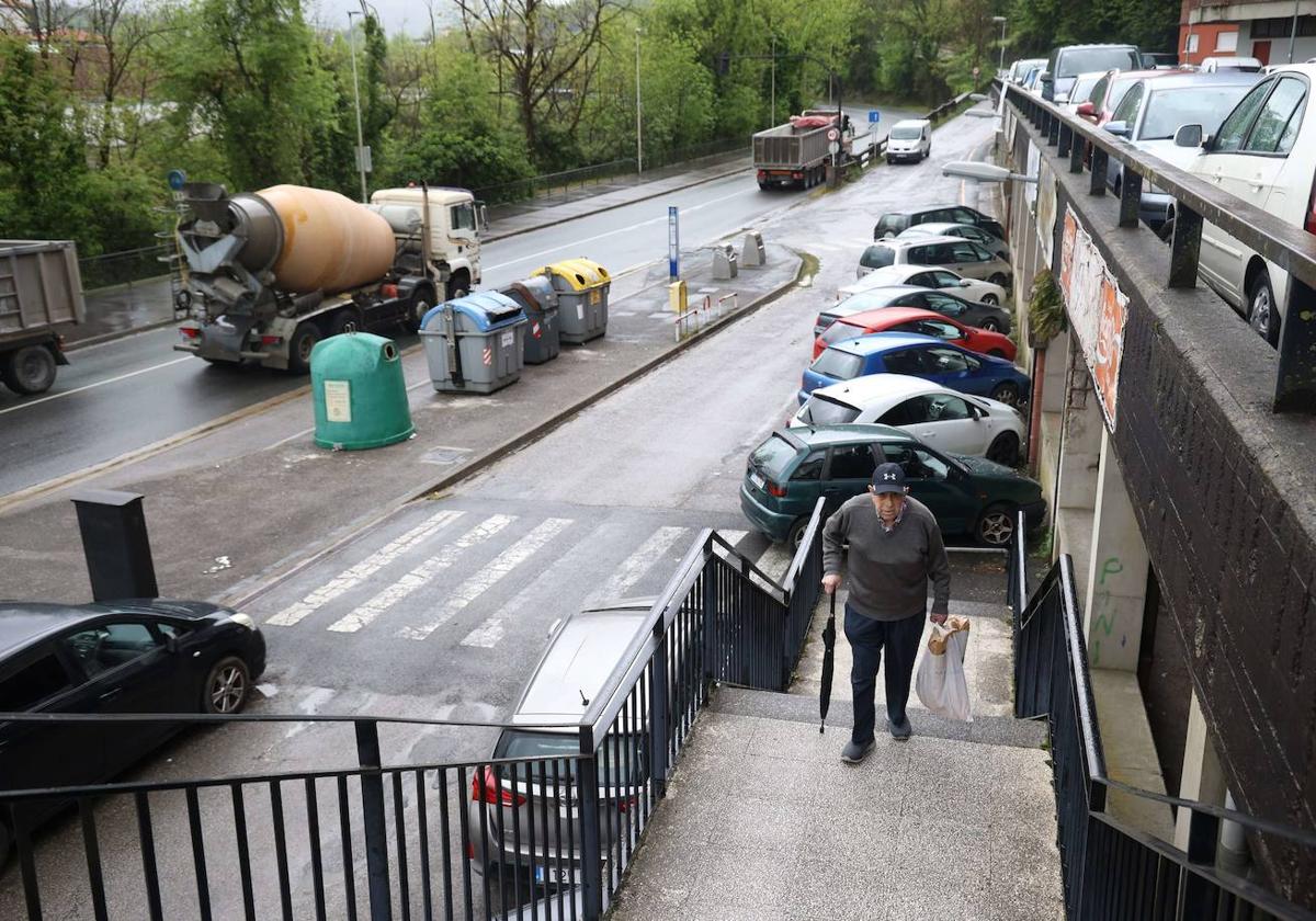 Un vecino del camino de la Hípica sube las escaleras, con la carretera de la discordia al fondo.