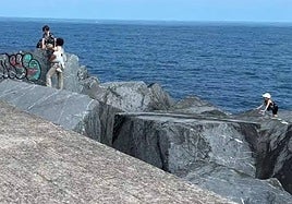 El padre, con sus hijos en las piedras del Paseo Nuevo de San Sebastián.
