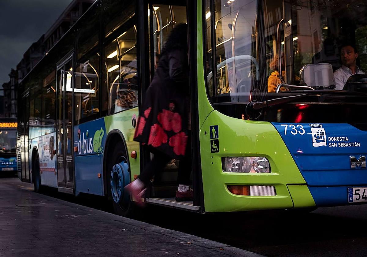 Una mujer sube de noche a un autobús de Dbus en la parada del Boulevard.