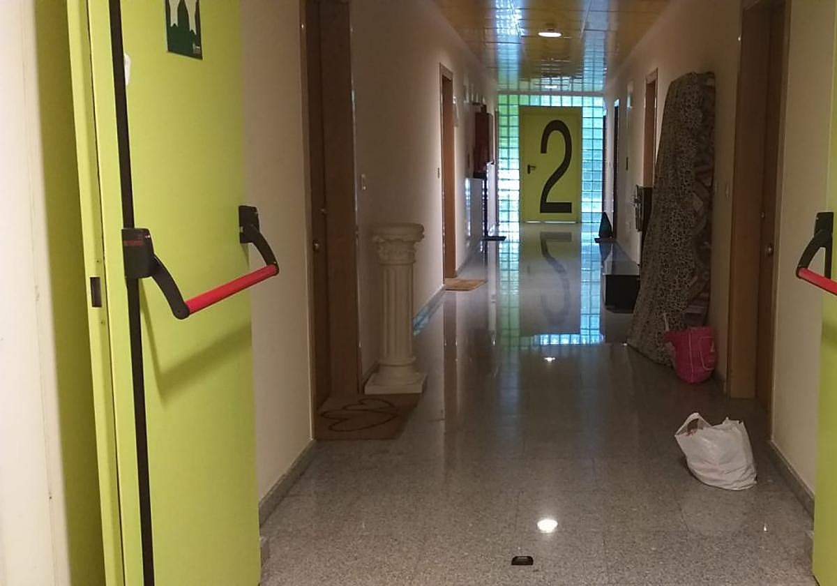 Pasillo del edificio con bolsas y un colchón.