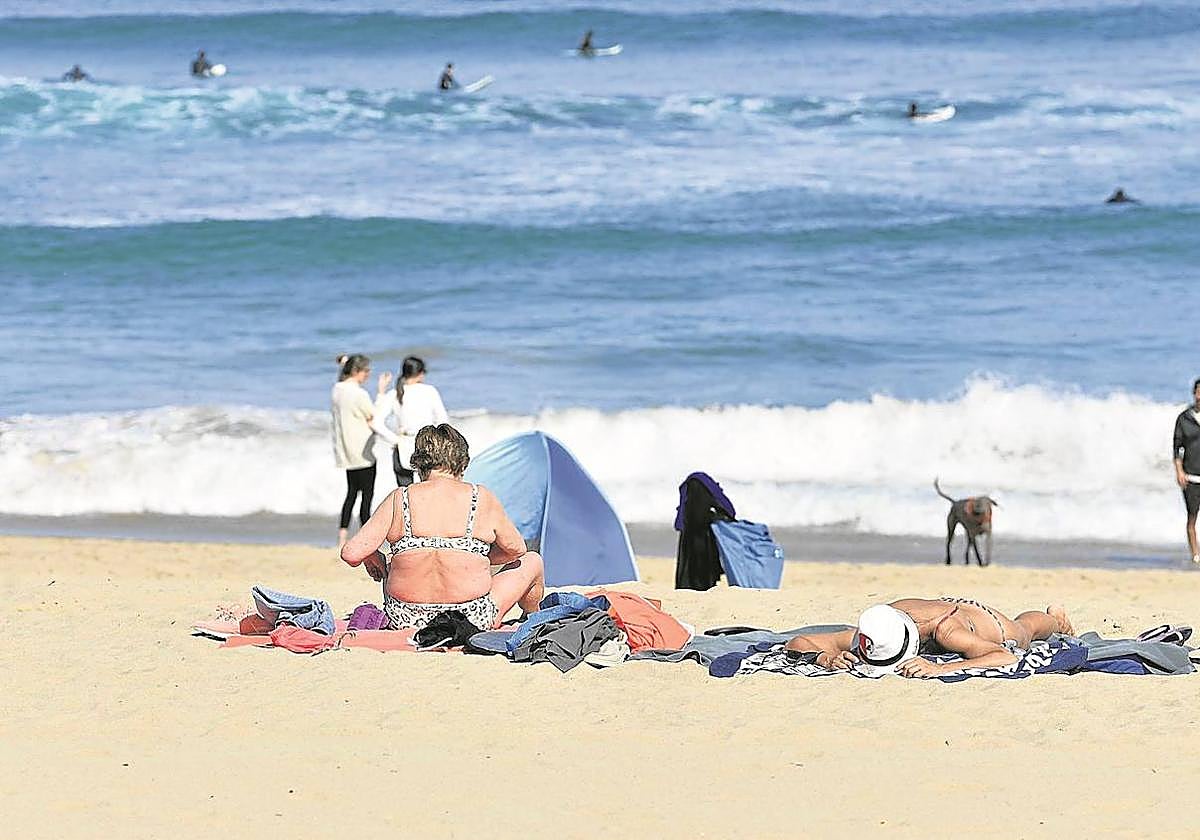 Dos mujeres toman el sol en la playa de la Zurriola de Donostia. Protegerse con crema solar es fundamental para prevenir el cáncer de piel.