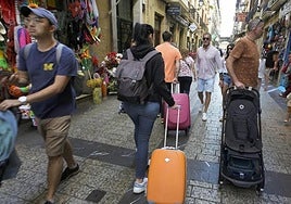 Dos turistas pasean con una maleta por las calles de la Parte Vieja de Donostia.