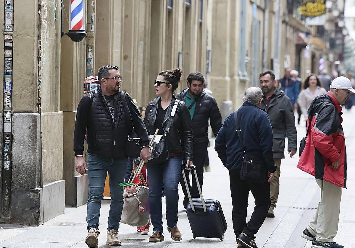 Unos turistas caminan con maletas por la Parte Vieja donostiarra.