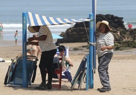 Dos de las personas contratadas por el Ayuntamiento para ofrecer el servicio de toldos, trabajando en la playa de Santiago.