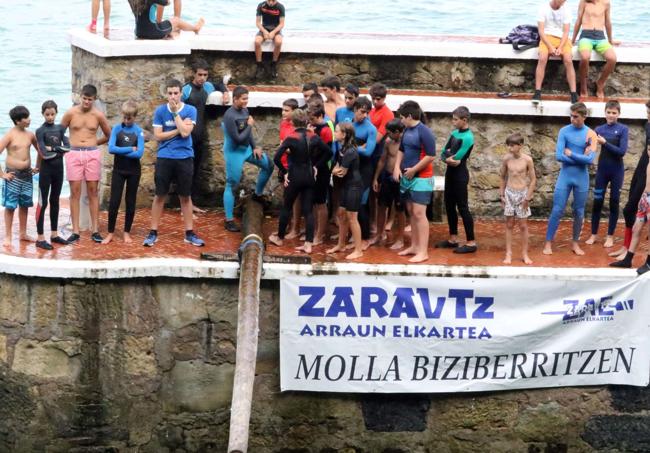 Jóvenes disfrutan de la cucaña en el puerto de Zarautz