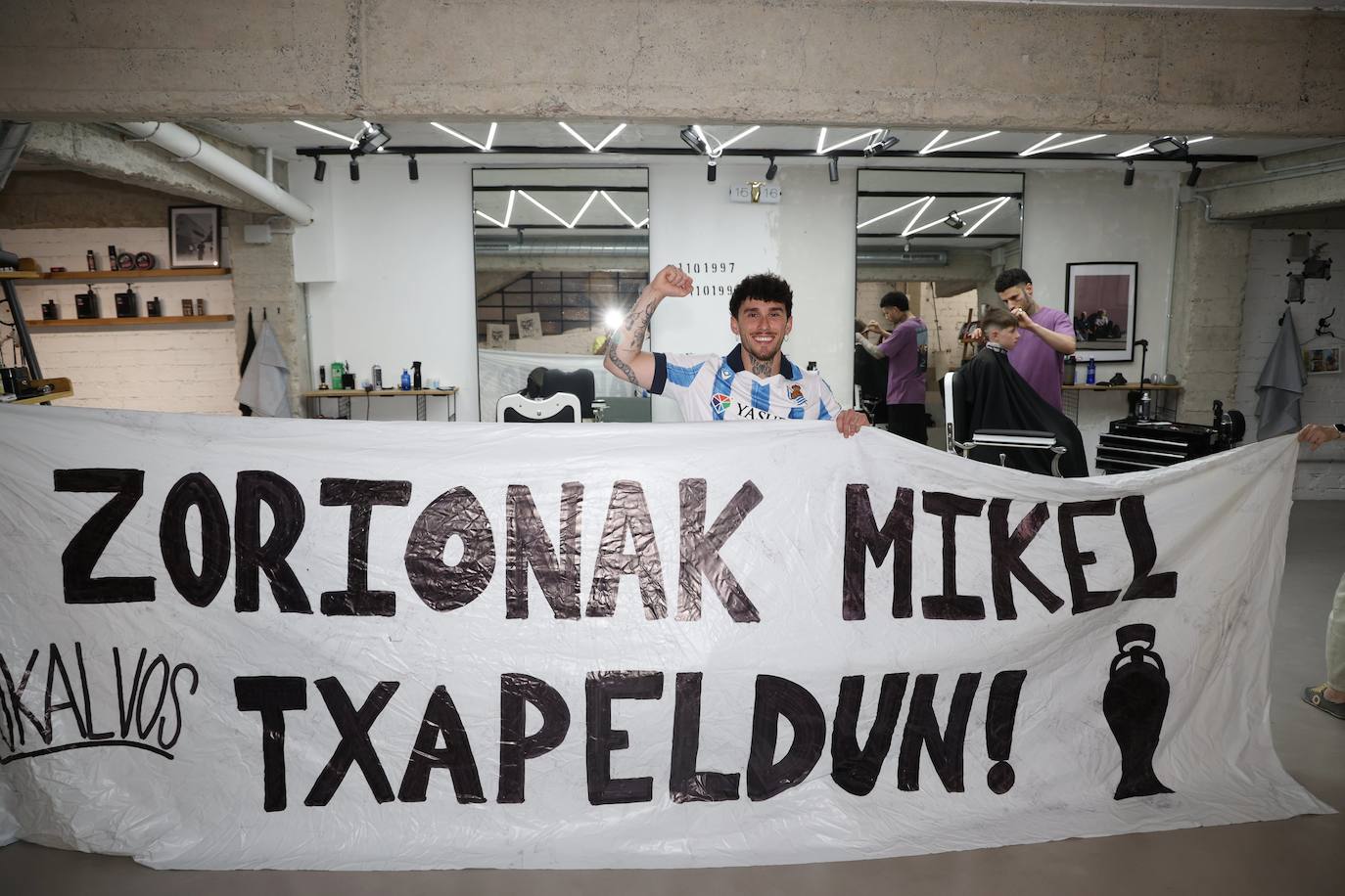 Alex Muguruza, amigo íntimo de Oyarzabal y organizador del recibimiento al capitán en Eibar, posa con la pancarta en su peluquería