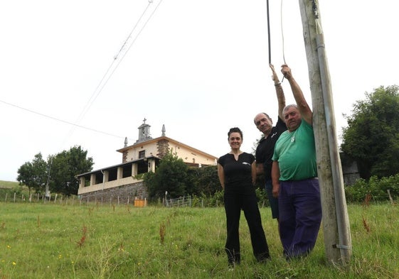 Cristina López, Iñaki Urbieta y Joxe Angel Egaña, junto al poste en el que se inició el robo del cable de telefonía, con la ermita del Kalbario al fondo.