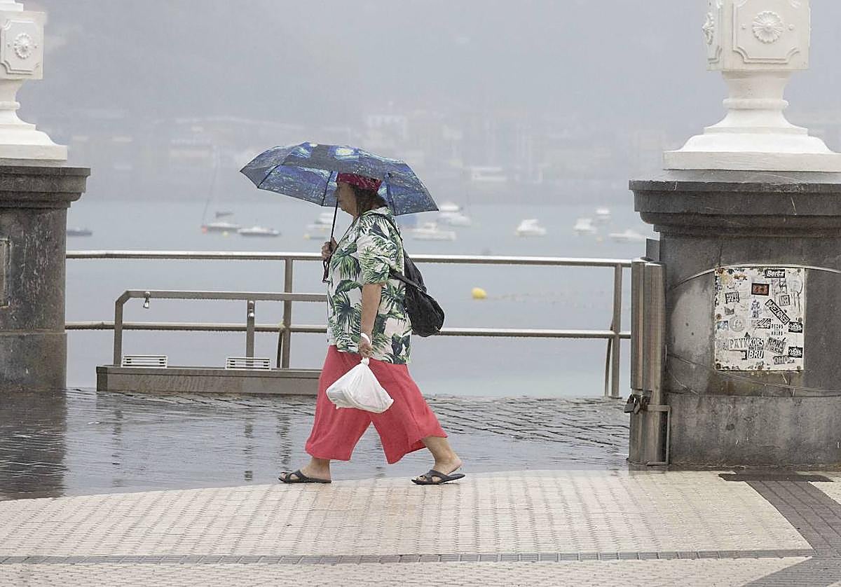 Una mujer caminando bajo la lluvia en Donostia.