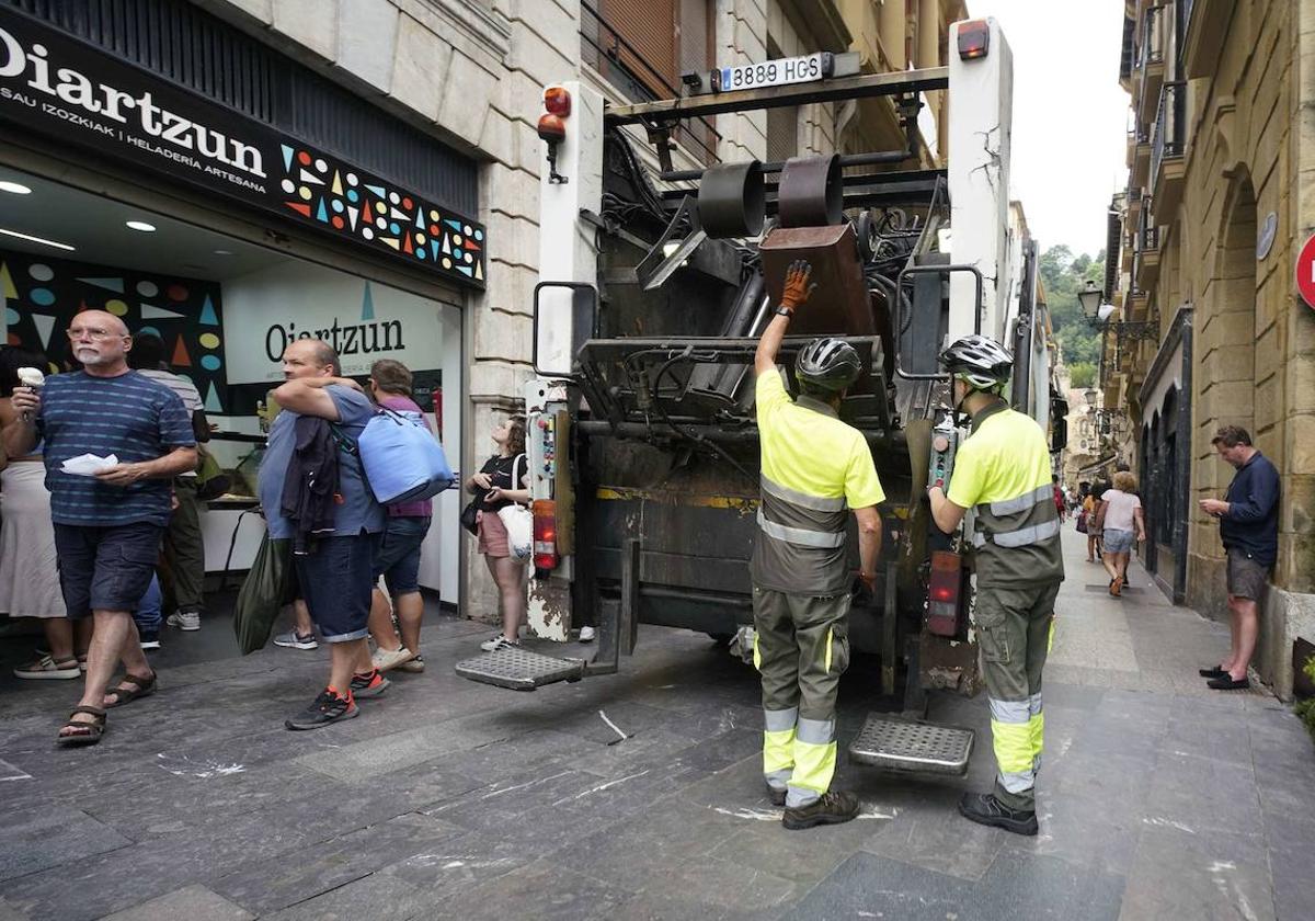 Dos operarios recogen la basura con la ayuda de un camión en la Parte Vieja.