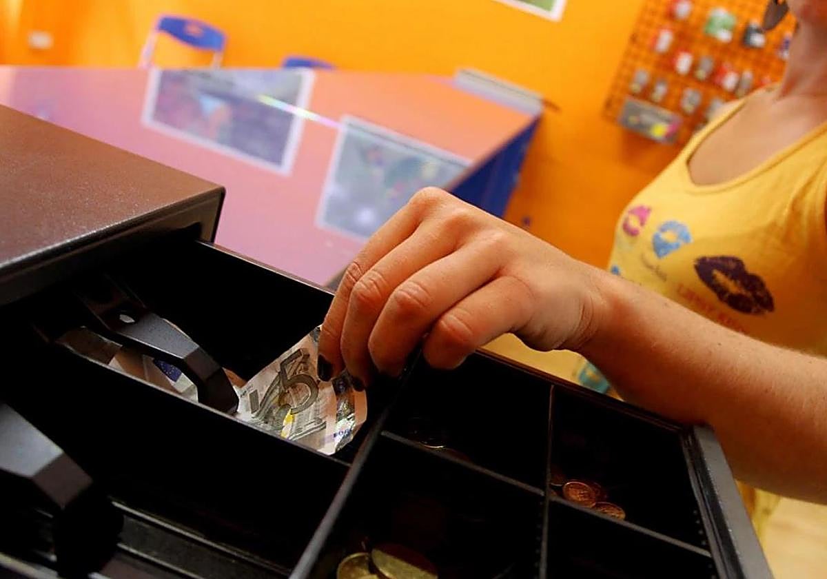 Una camarera ajena a la información saca dinero de la caja registradora.