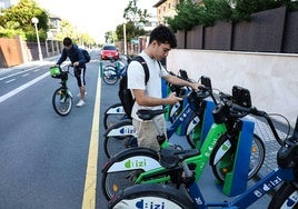 Dos jóvenes cogen bicicletas eléctricas en la estación de Dbizi en Ondarreta.