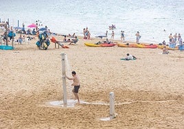 Un hombre se ducha en la playa para tratar de combatir el calor.