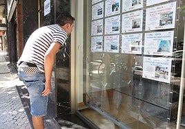 Un joven mira el escaparate de una inmobiliaria.