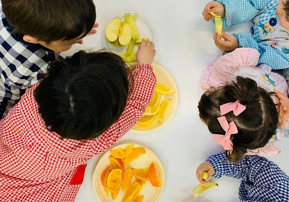 Niños y niñas prueban diferentes frutas durante una clase.