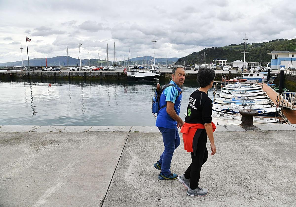Un hombre y una mujer pasean por el puerto de Getaria.