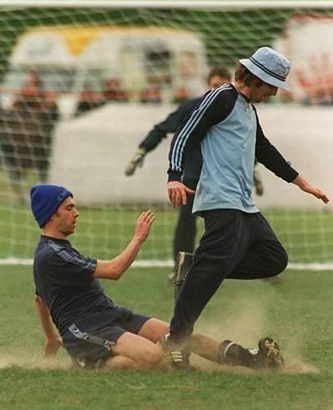 Damon Albarn y Liam Gallagher disputan un balón.
