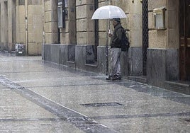 Un hombre se refugia de la lluvia en la Parte Vieja de Donostia.