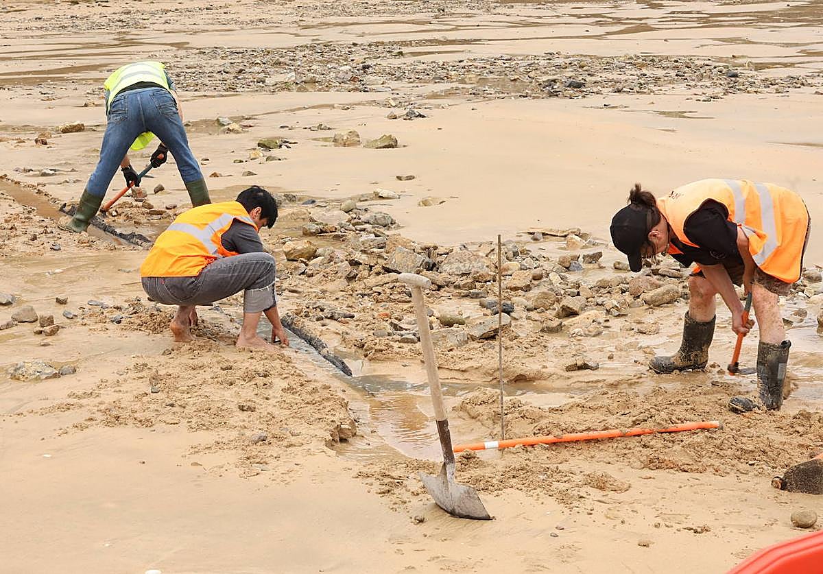 Técnicos examinan la fila curva de maderas aparecida ayer en la playa de Ondarreta.