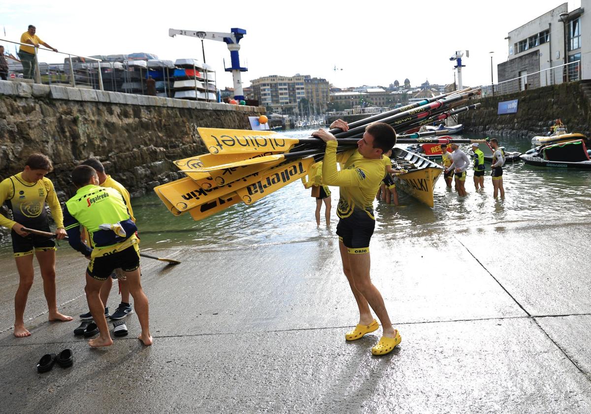 Un remero de Orio porta los remos en la rampa del muelle.