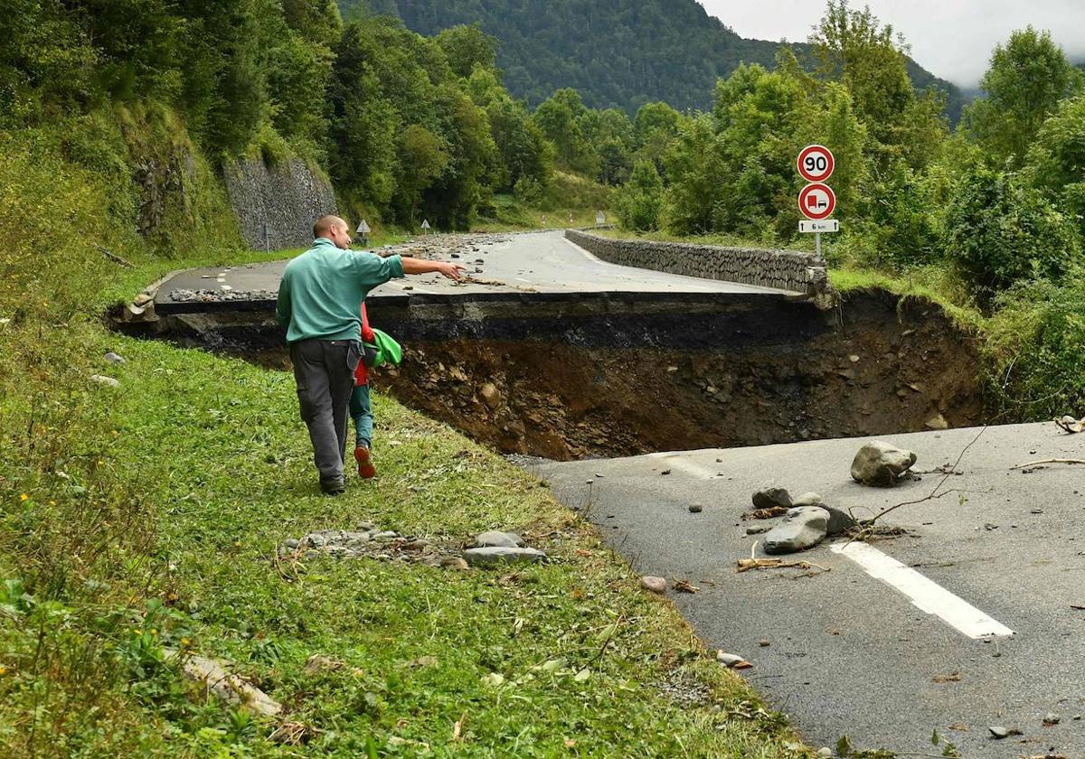 Un padre camina junto a su hijo al lado del enorme socavón producido por las fuertes lluvias del fin de semana.