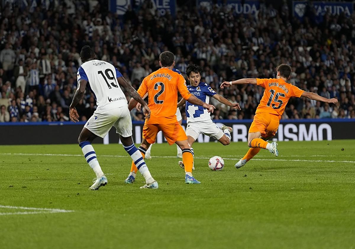 Take Kubo arma la pierna para disparar con Arda Güler tratando de frenar el disparo.