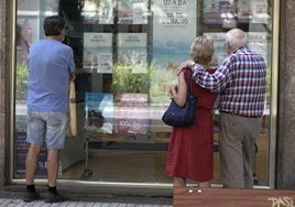 Varias personas observan las ofertas de una agencia de viajes.