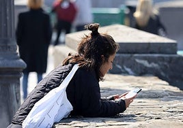 Una joven mira su teléfono en la calle.