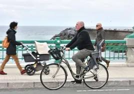 Un hombre atraviese en su bicicleta el puente del Kursaal en San Sebastián.