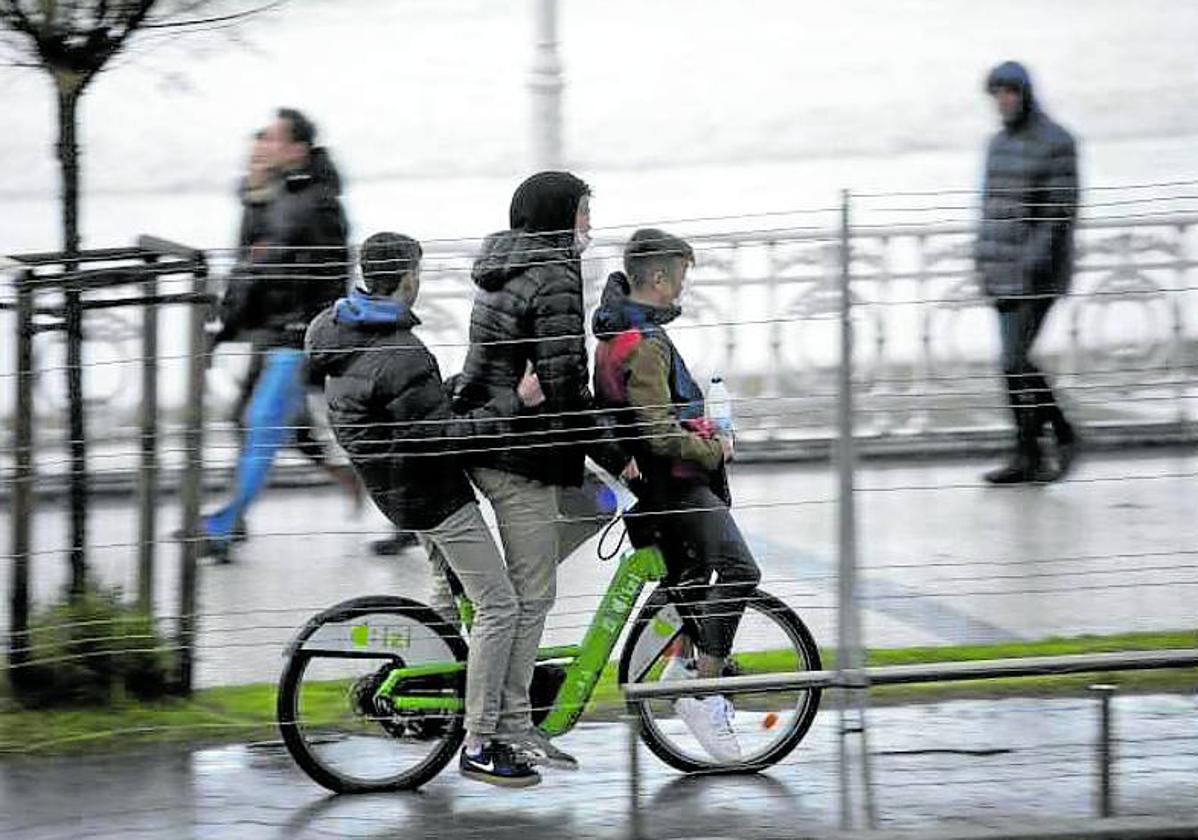 Tres jóvenes circulan en una bicicleta por La Concha, algo totalmente prohibido.