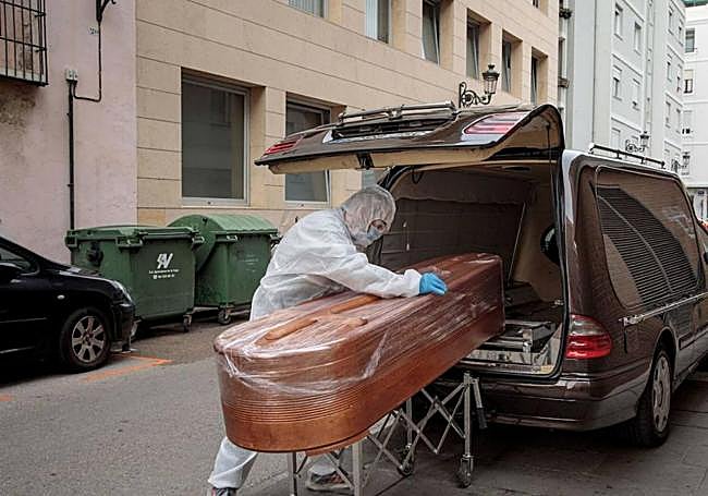 Introducción de una caja mortuoria en un coche fúnebre.