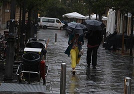 Una pareja pasea bajo la lluvia en una calle del centro de San Sebastián a primera hora de esta mañana.