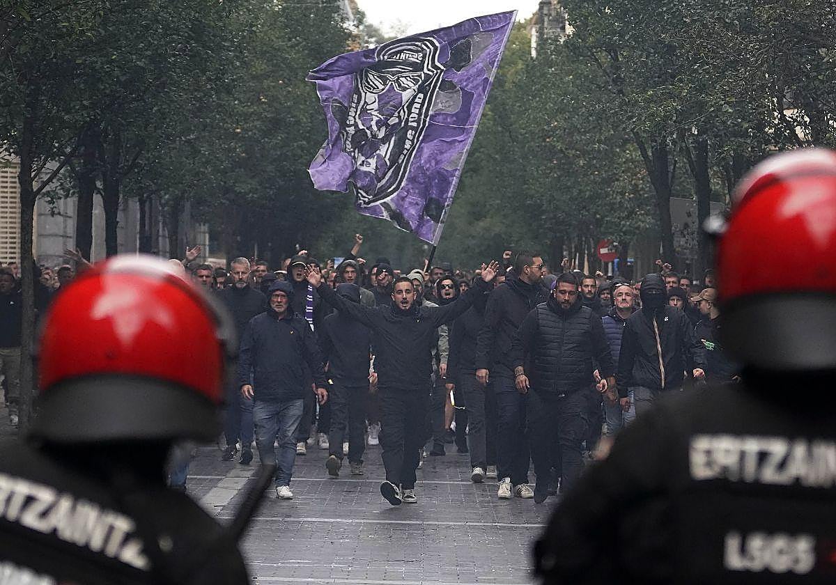 Dos Ertzainas, frente a un grupo de ultras del Anderlecht el pasado jueves en San Sebastián horas antes del encuentro frente a la Real Sociedad.