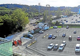 Aparcamiento en superficie sobre el que se va a acometer la ampliación del Hospital Donostia, con Onkologikoa al fondo. A la izquierda, la parcela donde se construye el parking provisional.