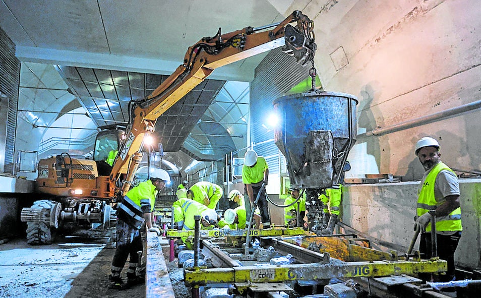 Imagen principal - Revestimiento de la galería con hormigon, montaje de las vías y operarios pasando por el entramado de la contravóbeda de la estación Centro.