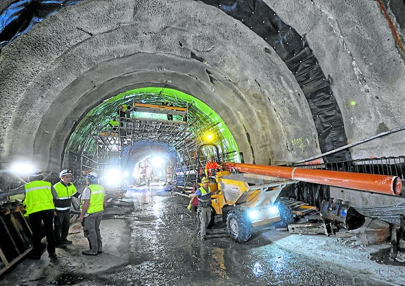Imagen secundaria 1 - Revestimiento de la galería con hormigon, montaje de las vías y operarios pasando por el entramado de la contravóbeda de la estación Centro.