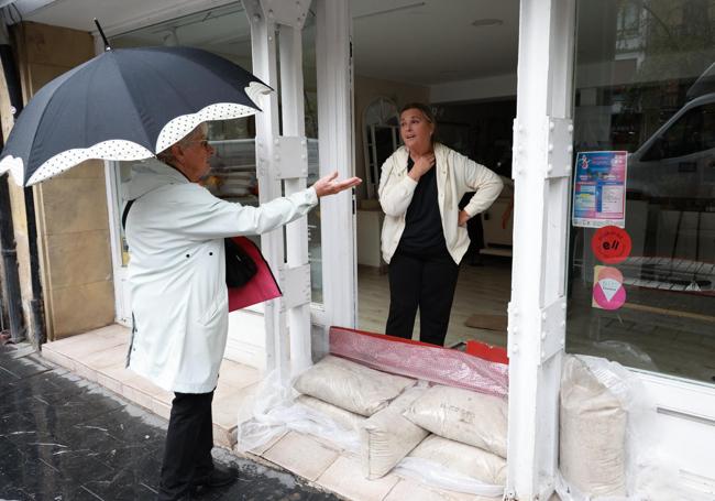 La propietaria de la tienda de mueble La Coquine atiende a una vecina que se ha interesado por los daños provocados por las lluvias en el establecimiento