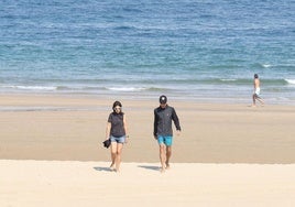 Personas pasean por la playa en Donostia.