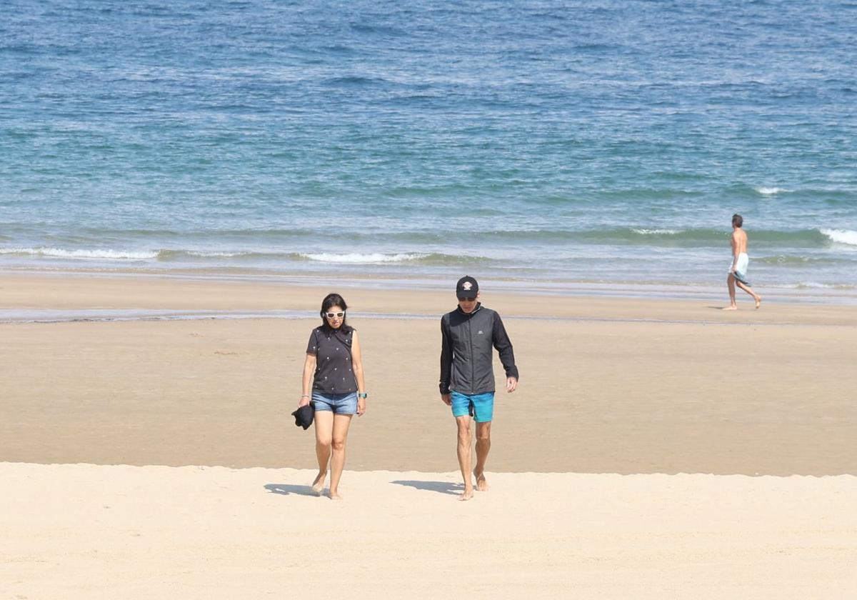 Personas pasean por la playa en Donostia.