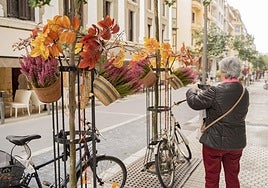 Una vecina de Gros saca una fotografía a la ornamentación otoñal colocada por la Sociedad de Fomento en la calle San Francisco de Gros este martes.