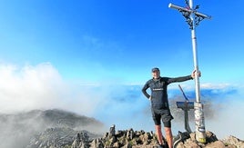 Carlos Morán sujeta la cruz de Aizkorri en la cima a la que ha subido centenares de ocasiones.