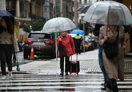 Varias personas se refugian de la lluvia bajo el paraguas en Donostia.