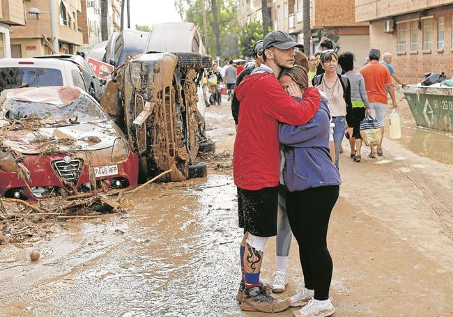 Una pareja se abraza ante la desolación en Paiporta, Valencia.