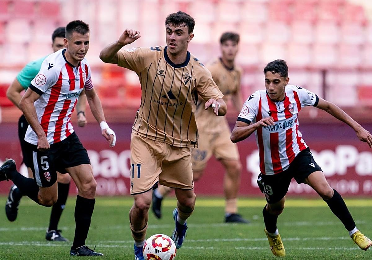 Endika Mateos controla la pelota ante varios jugadores de la UDL.