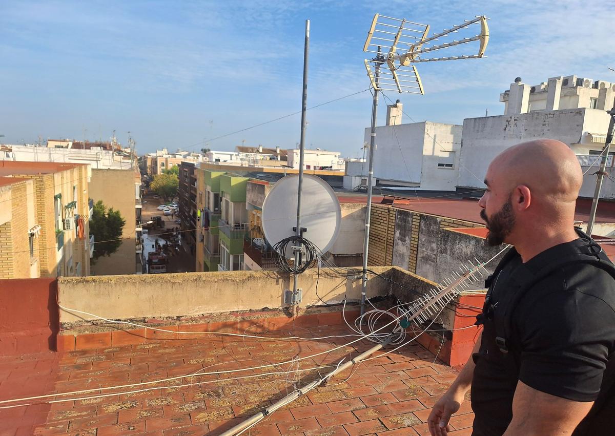 Imagen secundaria 1 - Aitor se sube a la escalera para salir por la trampilla del techo, tal y como hizo el día de la tragedia, cuando un amión atravesó el bajo del edificio donde vive en Benetússer. 