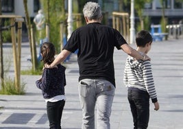 Un padre pasea con sus hijos por Donostia.