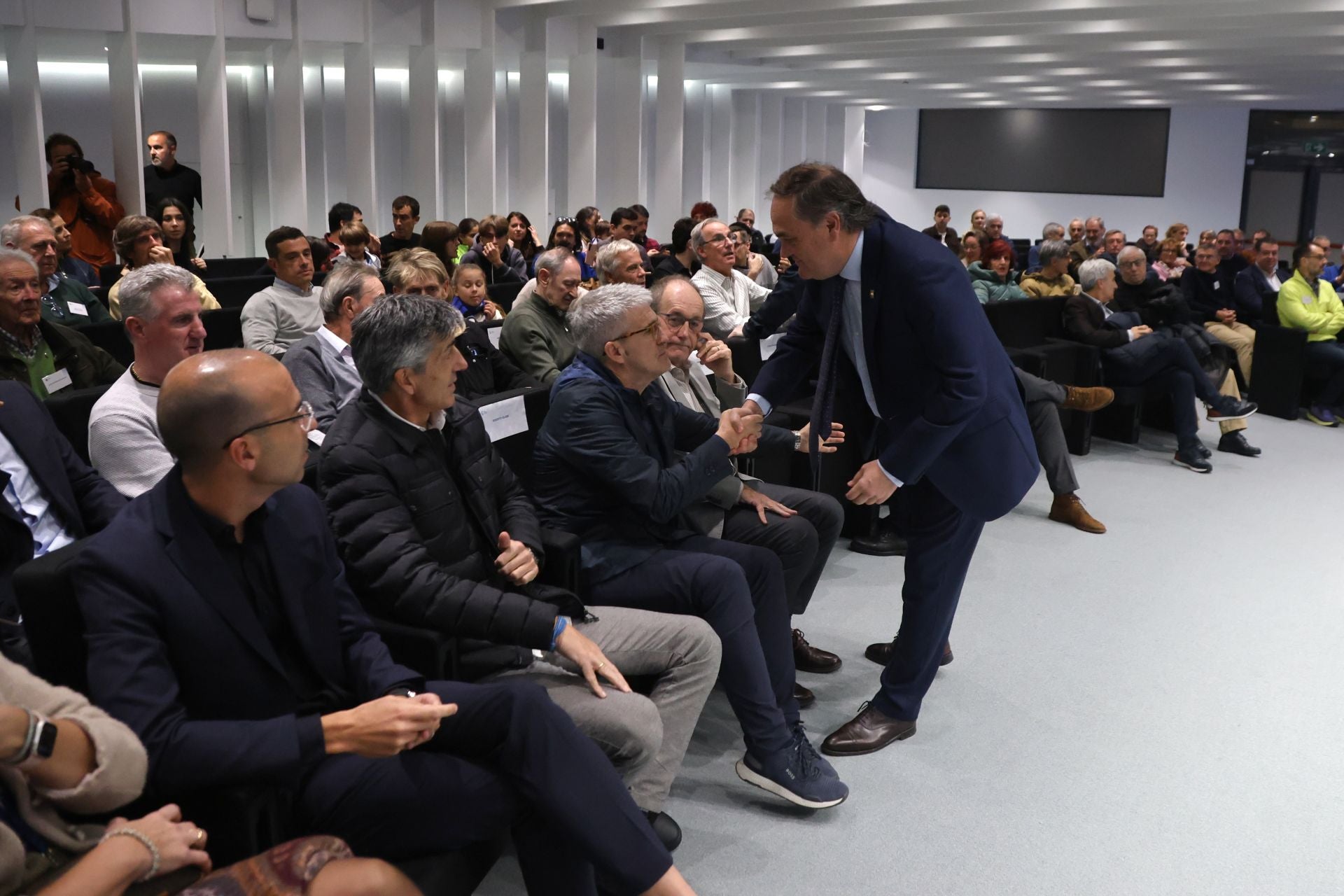 Jokin Aperribay estrecha la mano de Roberto Olabe ante la mirada de Imanol Alguacil.